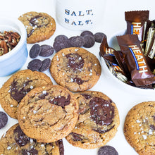 Load image into Gallery viewer, many gourmet chocolate chip cookies with guittard chocolate, heath, salt, and toasted pecans in the background
