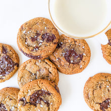 Load image into Gallery viewer, a few gourmet chocolate chip cookies with maldon salt, next to a glass of milk
