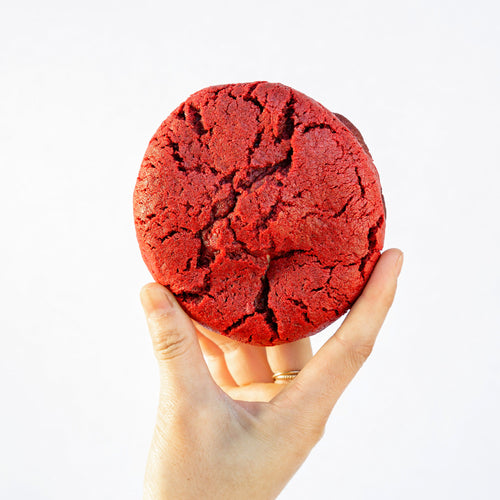 holding a single red velvet pudge cookie to the light, revealing beautiful cracks on the surface